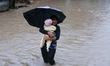 A Nepali woman carries a baby and wades through floodwater in Kathmandu, Nepal, on Septemb...
