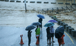 Residents of Kathmandu stand on the embankment of a flooded river in Kathmandu, Nepal, on...