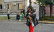A resident of a multi-storey building damaged by a Russian airstrike carries a dog in her...