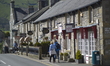 People passing a row of shops in Castleton, Derbyshire, England, United Kingdom on Sunday...