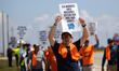 Dockworkers and their supporters hold signs during a strike outside the Bayport Container...