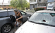 A woman stands next to cars damaged by Russian shelling in Zaporizhzhia, Ukraine, on Octob...
