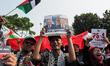 A pro-Palestinian demonstrator holds a poster with photos of Israeli Prime Minister Benjam...