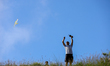 A Nepali man flies a kite from a hilltop surrounding Kathmandu Valley with the arrival of...