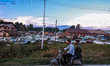 Kashmiri boys ride a scooter as seized and damaged vehicles are seen inside a yard on the...