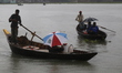 Residents cross over the Buriganga River by boat during the rainfall in Dhaka, Bangladesh,...