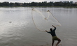 A man casts his fishing net in the Buriganga River in Dhaka, Bangladesh, on October 23, 20...