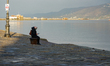 A woman enjoys the serene ambiance of the old harbor in Trieste, Italy, on a hazy winter m...