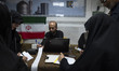 A veiled Iranian woman and Iranian men check a donated gold plaque and bank receipts for d...