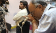 A trader checks the shape and color of a polished diamond inside a stall at East India's I...