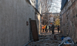 People stand behind caution tape at the buildings damaged by a Russian missile attack in c...