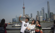 Tourists take selfie picture at the Bund as Lujiazui Financial district is seen behind dur...
