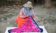 Weavers arrange sarees, a traditional cloth used for women's clothing, as they hang them o...