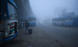 A person stands at a bus stand on a foggy morning in Kolkata, India, on January 5, 2025. 
