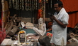 A Sadhu, or Hindu holy man, sits in his makeshift shelter as a pilgrim looks at his mobile...