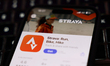 A laptop keyboard and Strava on App Store displayed on a phone screen are seen in this ill...