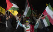 A group of Iranian people waves flags of Palestine, Iran, and Lebanon's Hezbollah while pa...