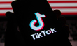 TikTok logo is screened on a mobile phone with US flag in the background for illustration...