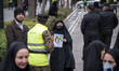 A veiled woman holds a poster featuring portraits of the Iranian senior judge, Mohammad Mo...
