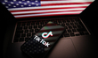 The TikTok logo displays on a phone with the US flag on a laptop screen in Krakow, Poland,...