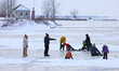A person skates on the frozen water of the Lachine Canal. Families participate in outdoor...