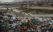 A stray dog rests on the garbage dump on the banks of the polluted River Jhelum in Baramul...