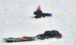 Children rest for a moment while sledding down a snow-covered hill following a snowstorm i...