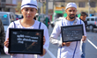 Demonstrators hold placards stating reasons for their symbolic imprisonment, demanding an...