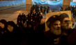 Veiled Iranian women arrive at Imam Khomeini Grand Mosque as one of them carries a poster...