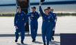 Mission Commander Anne McClain waves her hat to the media upon arrival at Kennedy Space Ce...