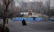 A veiled Iranian visitor walks past a banner featuring portraits of late leaders of Lebano...