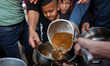 Palestinian children receive their family's share of an iftar fast-breaking meal at a free...