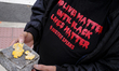 A person holds a brick and parts of a bold-yellow letter from the ''Black Lives Matter'' m...