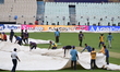 Ground staff cover the field at the Eden Gardens amid rain, ahead of an Indian Premier Lea...