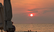 Tourists swim and relax on the beach as the sun sets over the sea on Phu Quoc Island. In P...