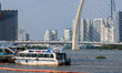A water transport boat docks near the Thu Thiem 2 Bridge across the Saigon River, with a b...