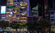 People walk and gather in front of the illuminated Cafe Apartment building on Nguyen Hue W...