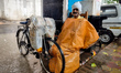 A newspaper vendor shields himself with plastic during heavy rain in Kolkata, India, on Ap...