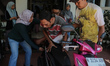 A volunteer (right) uses a motorbike to take a disabled patient home during one of the pat...