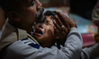 A crying child is hugged by an attendant during a neurotherapy service at a disability pos...