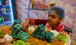 A baker in Kolkata, India, on May 10, 2025, stands in front of a custom cake with replicas...