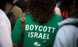 A woman holds a sign reading 'boycott Israel' during the gathering. A commemoration of the...