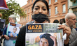 A woman holds a placard depicting a Palestinian woman killed, which reads 'Gaza: figures,...