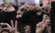 Iranian schoolgirls make heart-shaped hand gestures while participating in a ceremony comm...