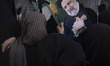 A veiled Iranian mourner holds a portrait of the late President, Ebrahim Raisi, during a c...