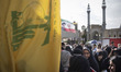 Veiled Iranian women stand together next to a flag of Lebanon's Hezbollah while participat...