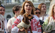 A woman in a traditional Ukrainian embroidered shirt holds a Dachshund on Vyshyvanka Day i...