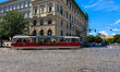 A red and cream-colored tram with vehicle number 8263 runs along a cobbled intersection pa...