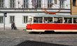 A red and cream-colored tram, vehicle number 6004, carries passengers through the cobbled...