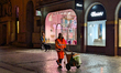 A municipal sanitation worker in a high-visibility uniform pushes a trash cart along a ped...
